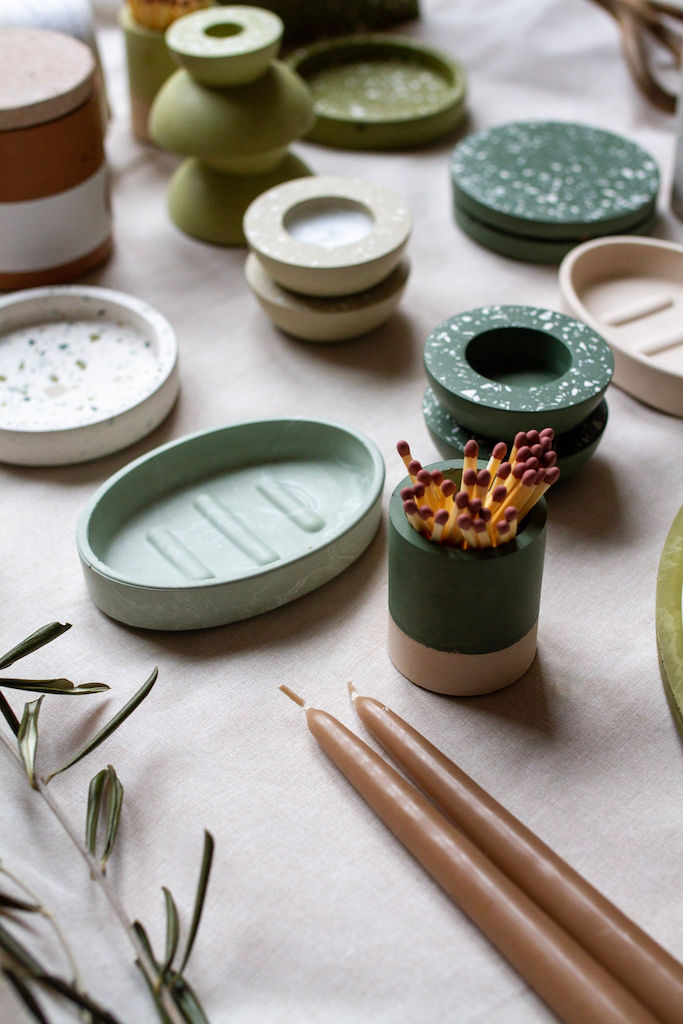 A selection of green, beige and white homeware pieces on a linen backdrop