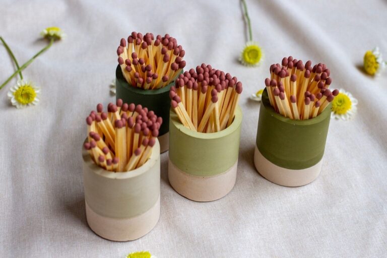 Four different green striker pots with daisies in background