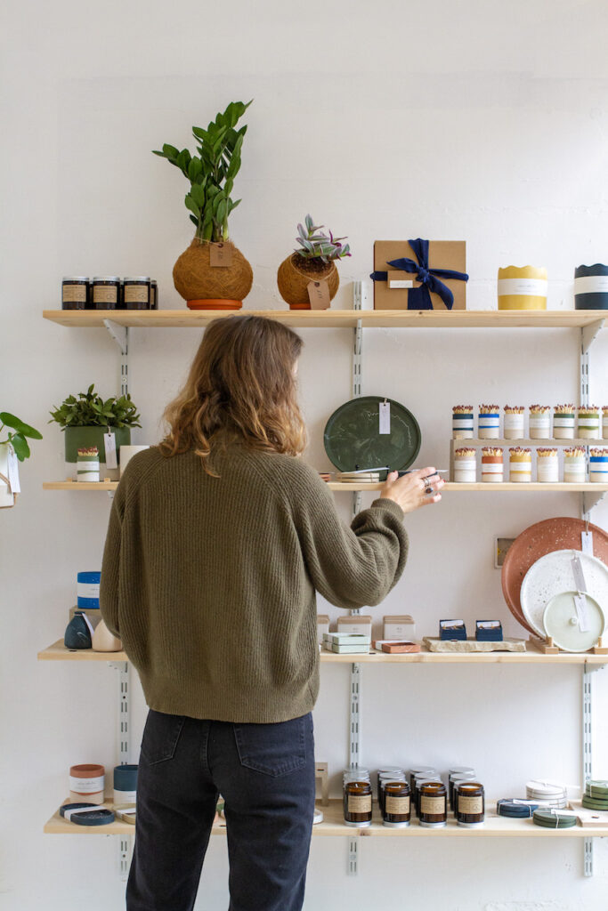 Calico Collective pop up shop in Didsbury with woman filling shelves with homeware