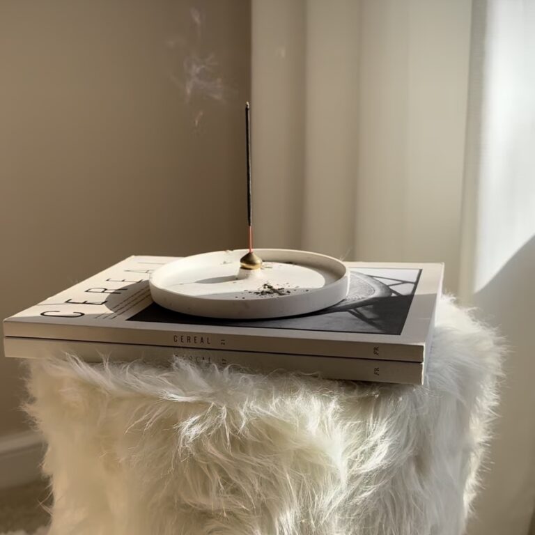 White seashell incense holder on fluffy stool with magazines